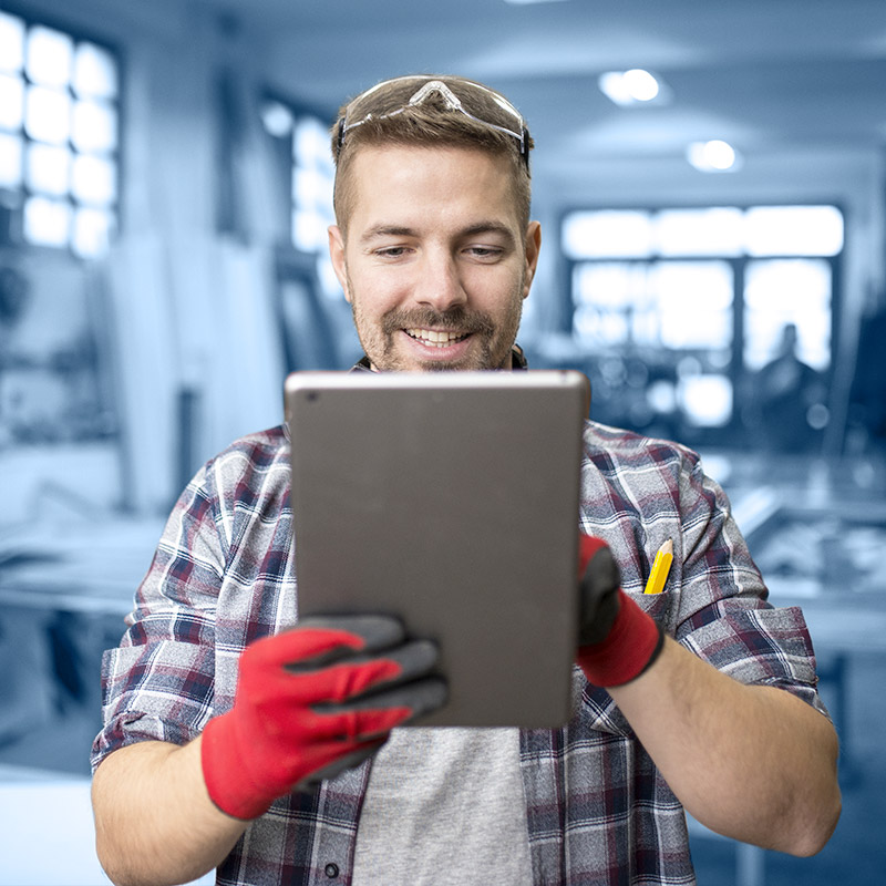 Un jeune homme, avec des lunettes de protection et des gants, qui utilise une tablette.
