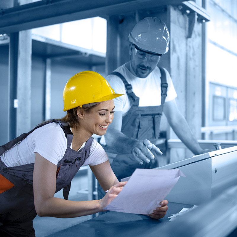 Deux employés souriants dans un local industriel.
