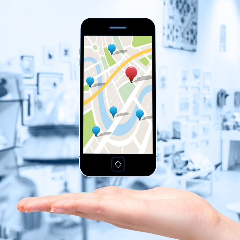 Un plan rapproché d'une main. Au-dessus de celle-ci lévite un téléphone portable qui affiche Google Map.